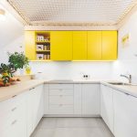 Kuchyňa do U so žltými skrinkami a sieťou nad hlavou
