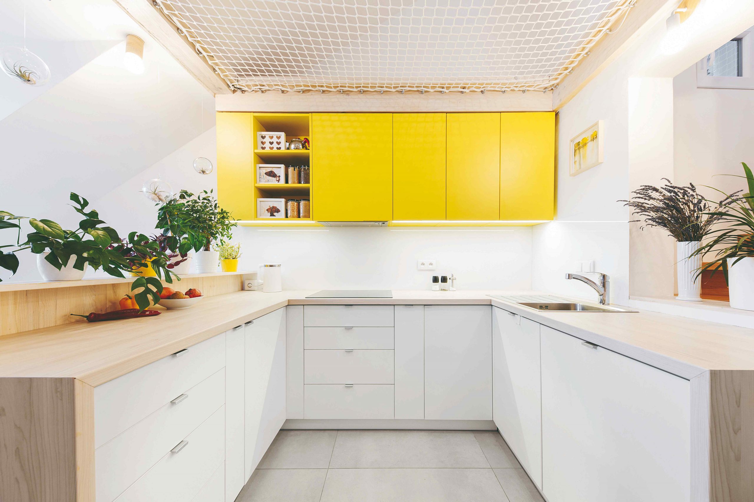 Kuchyňa do U so žltými skrinkami a sieťou nad hlavou