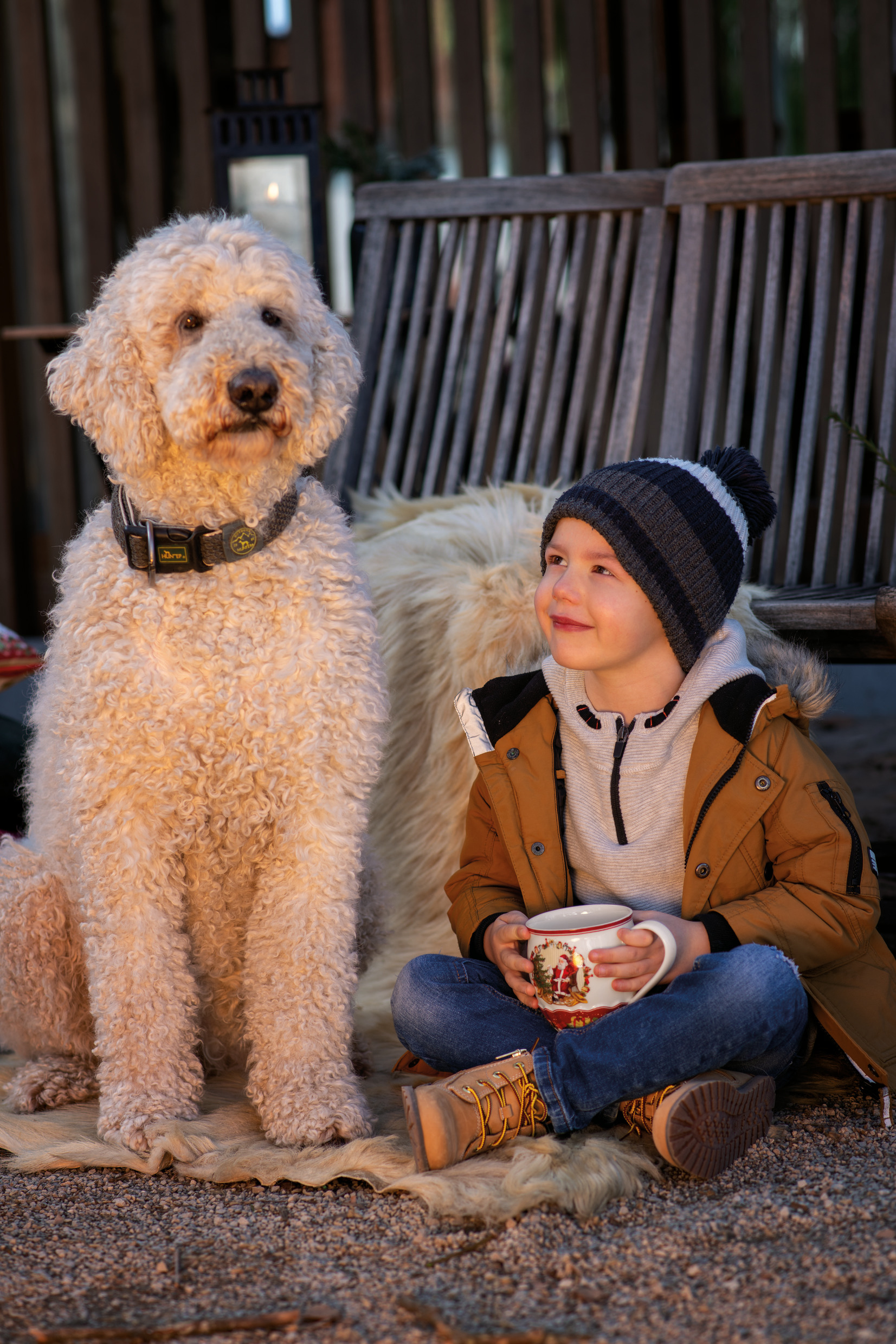 Chlapček s velkým psom pije čaj v zime