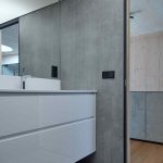 Betónová kúpeľňa s bielom skrinkou a celoplošným zrkadlom