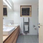 Kúpeľňa s čiernobielou podlahou a drevenými skrinkami