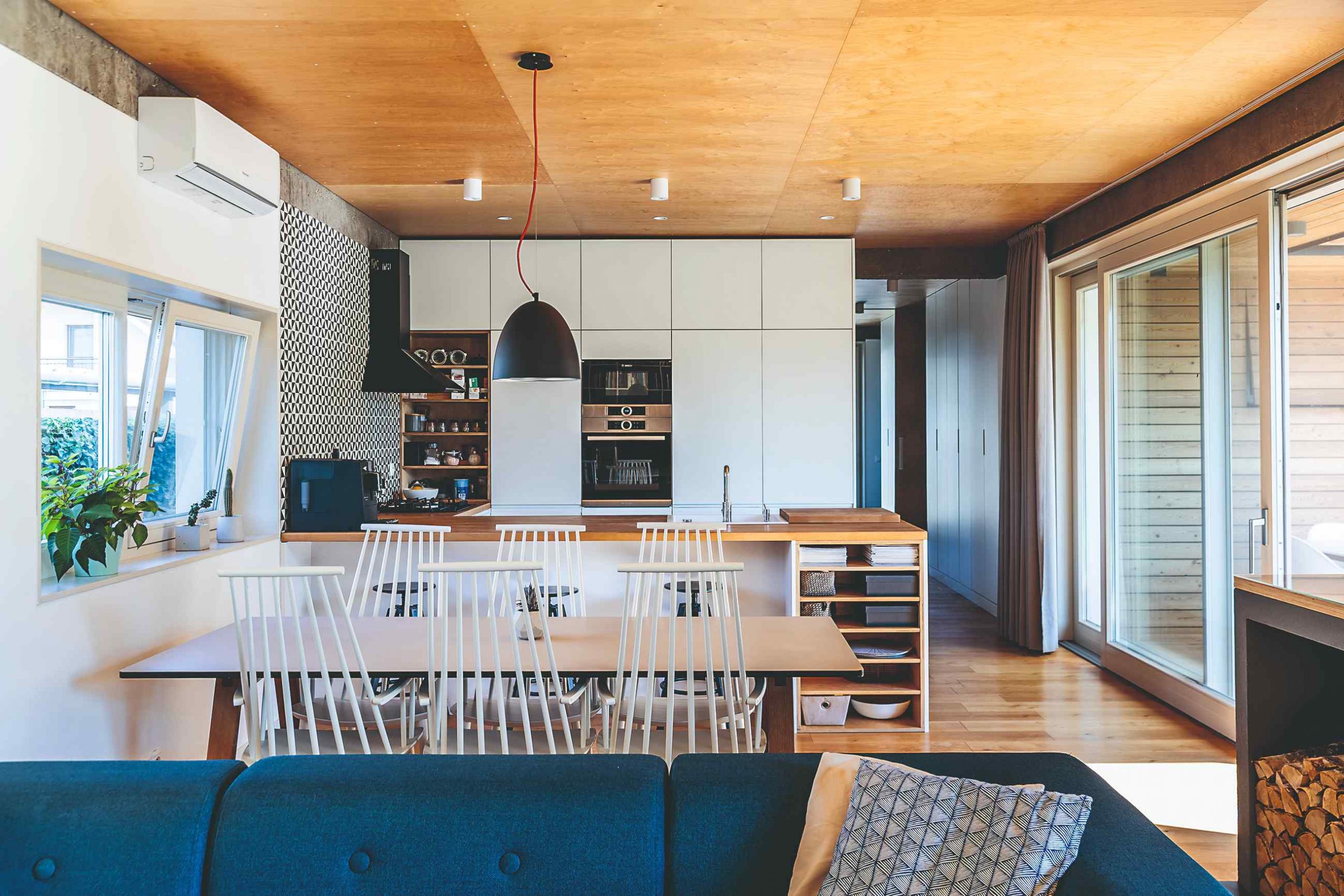 Jedáleň s dizajnovými stoličkami a bielo drevená kuchyňa v dome