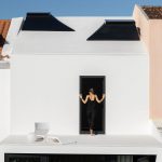 Malá biela terasa v úzkom dome so strešnými svetlíkmi