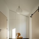 Chodba s dizajnovým svietidlom, stoličkou a šikmou úložnou stenou
