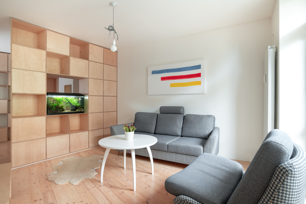 Obývačka s policovou stenou akváriom a sivou sedačkou