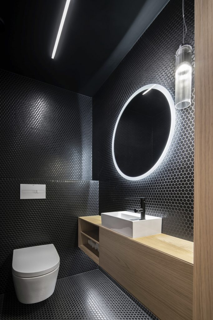Čierna toaleta s veľkým okrúhlym zrkadlom a umývadlom