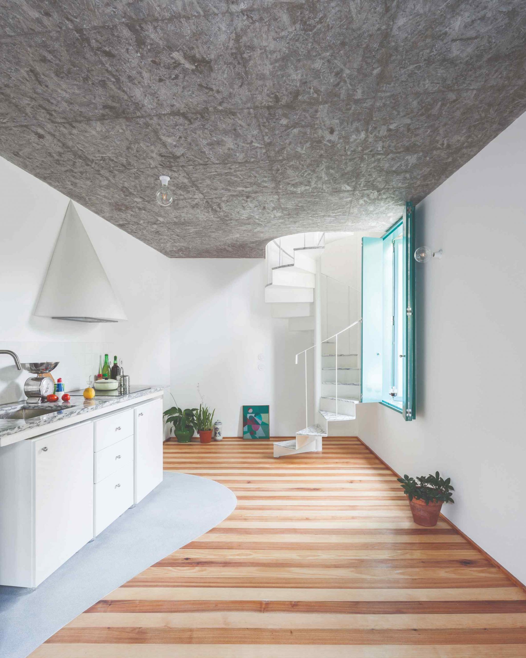 Kuchyňa s pruhovanou podlahou a s malým točitým schodiskom