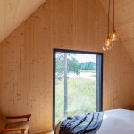 Spálňa v dome zo svetlého dreva s veľkým oknom do prírody