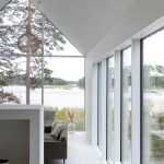 Biely interiér rodinného domu s presklenou fasádou s výhľadom na more