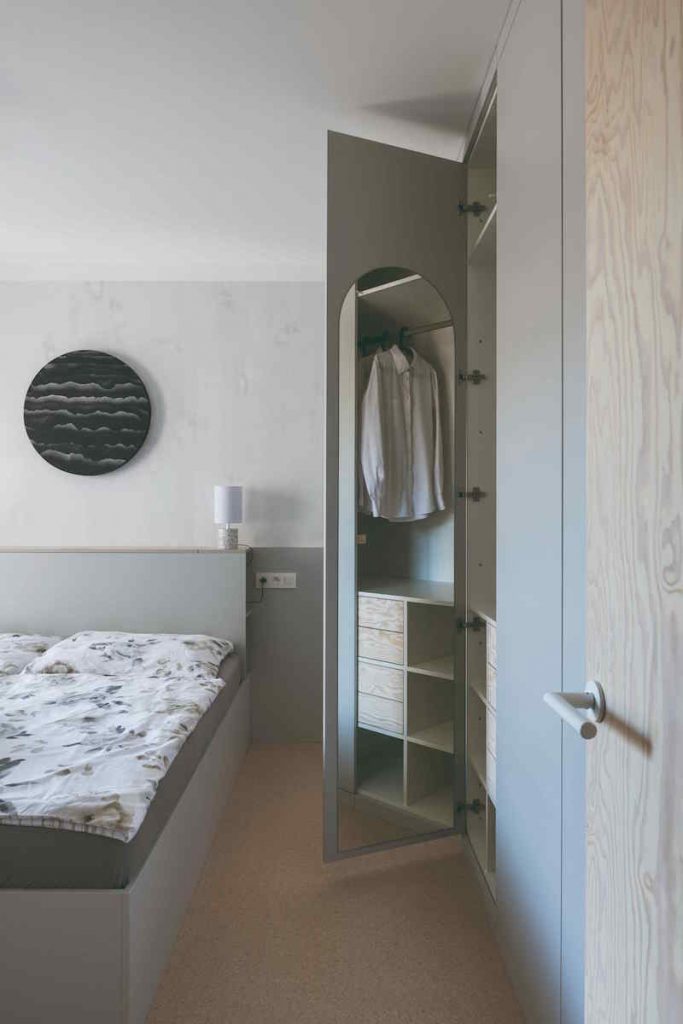 Jednoduchá sivá spálňa s kruhovým obrazom nad posteľou