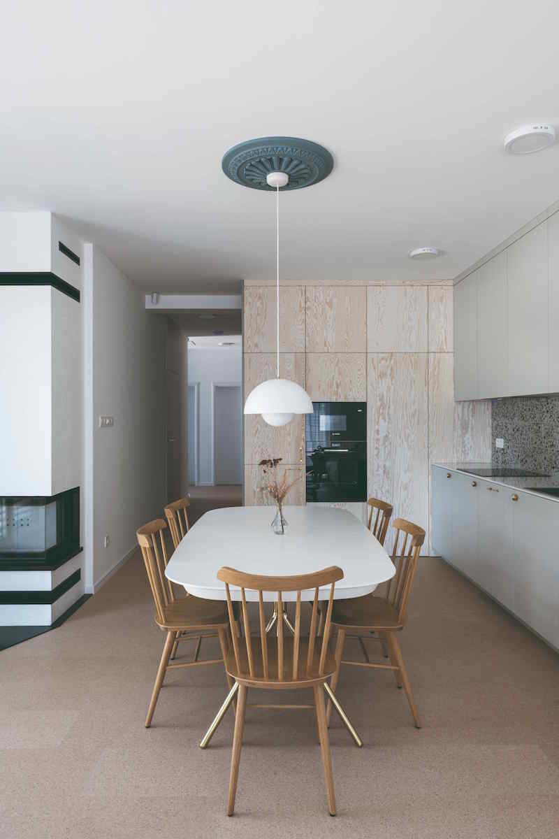 Moderná sivá kuchyňa s retro jedálňou uprostred a krbom v rohu
