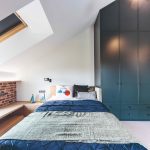 Podkrovná spálňa s modrou skriňou po strop a modrým prehozom