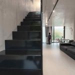 Čierne kovové schody v jednoduchej industriálnej obývačke
