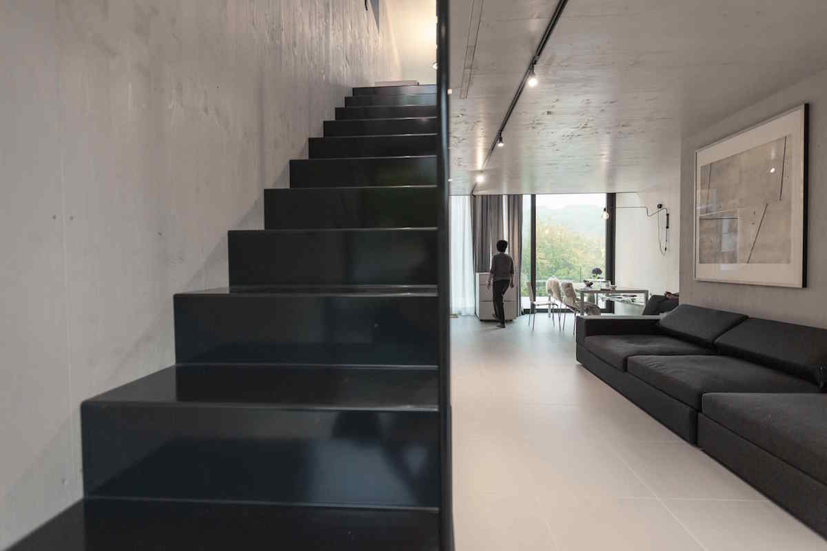 Čierne kovové schody v jednoduchej industriálnej obývačke