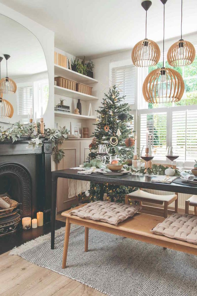 Prírodný interiér s krbom vianočným stolom a stromčekom v štýle hygge