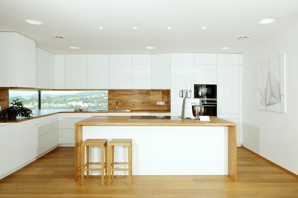 Veľká biela kuchyňa so svetlým drevom a ostrovčekom