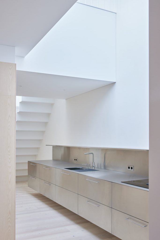 Biela kuchyňa s kovovou linkou v podkroví