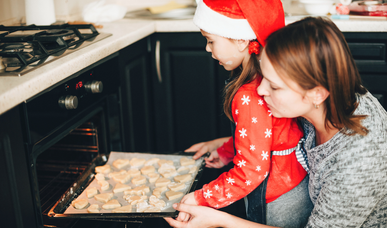 Christmas preparation by a caucasian family by cooking cakes in the oven wearing red holiday clothes