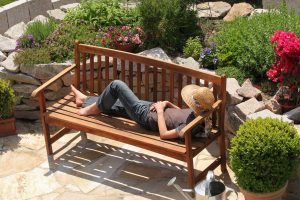Žena relaxuje na lavičke v záhrade