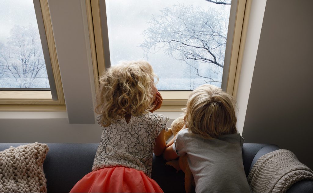Deti pozeraju cez strešné okno na stromy