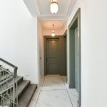 Chodba domu s mramorovou podlahou a zelenými dverami