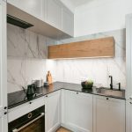 Biela malá kuchyňa s mramorovou zástenou a parketami