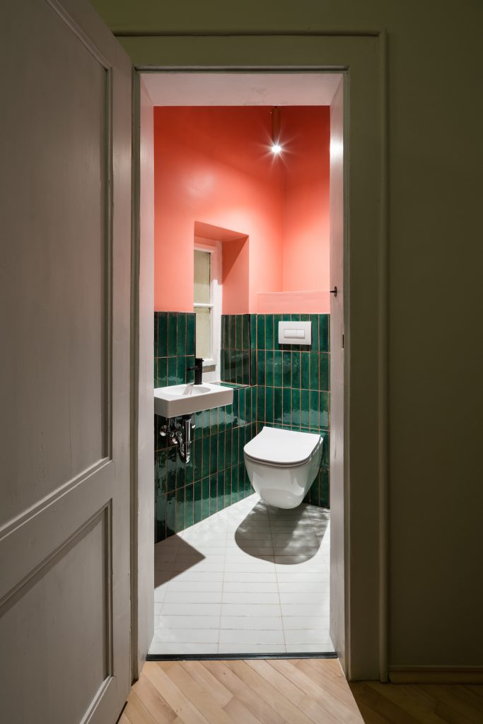 Žiarivo oranžová toaleta so zelenými kachličkami