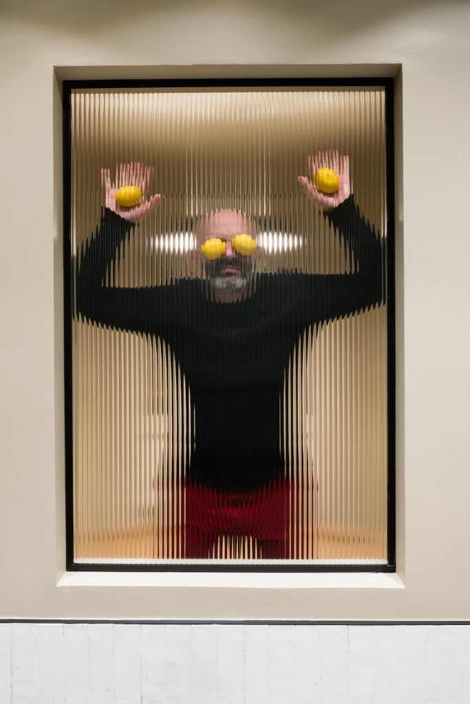 Muž s citrónami na očiach a vrukách vo vrúbkovanom okne