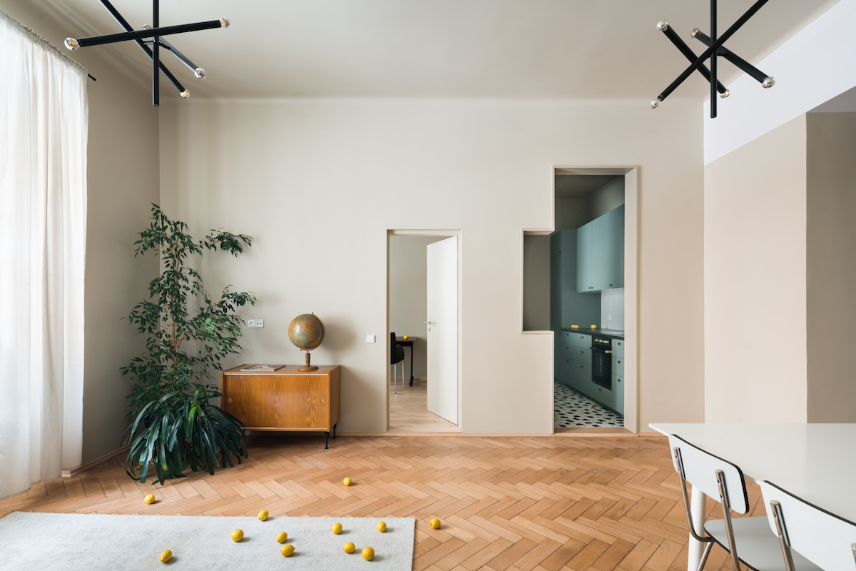 Retro obývačka s parketami a geometrickým výrezom do kuchyne