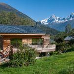 Alpská chata s dreveným obkladom v horskom prostredí v pozadí Alpy