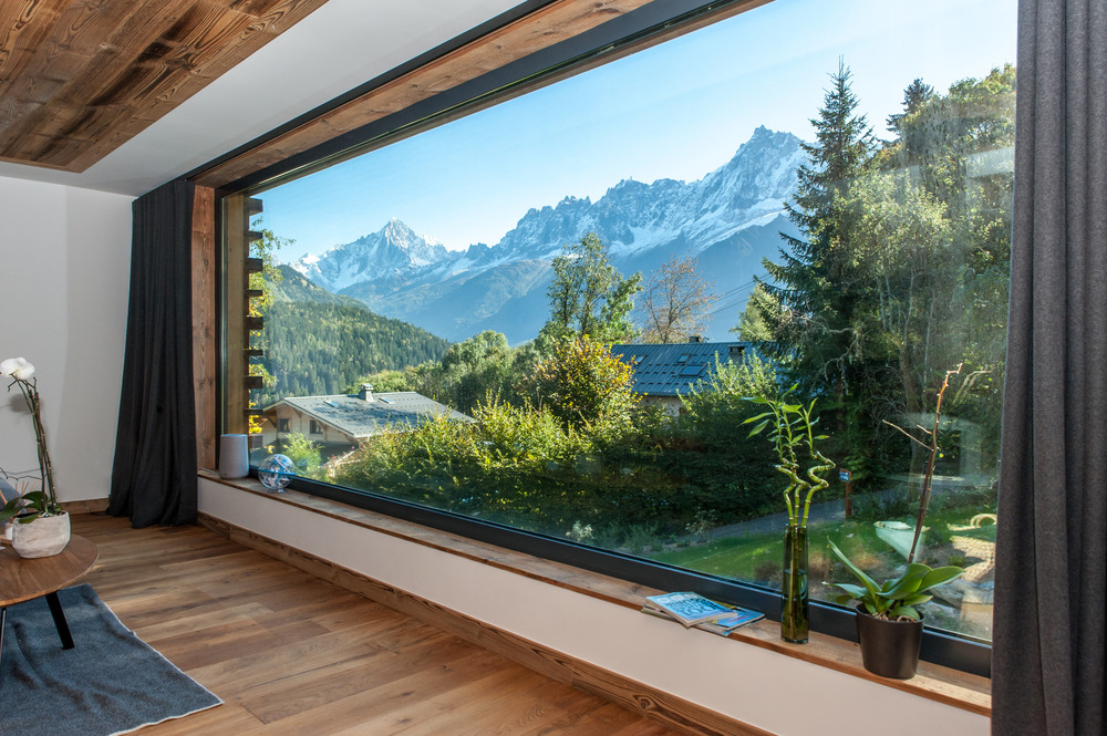 Alpská chata s veľkorozmerným oknom s výhľadom na Alpy