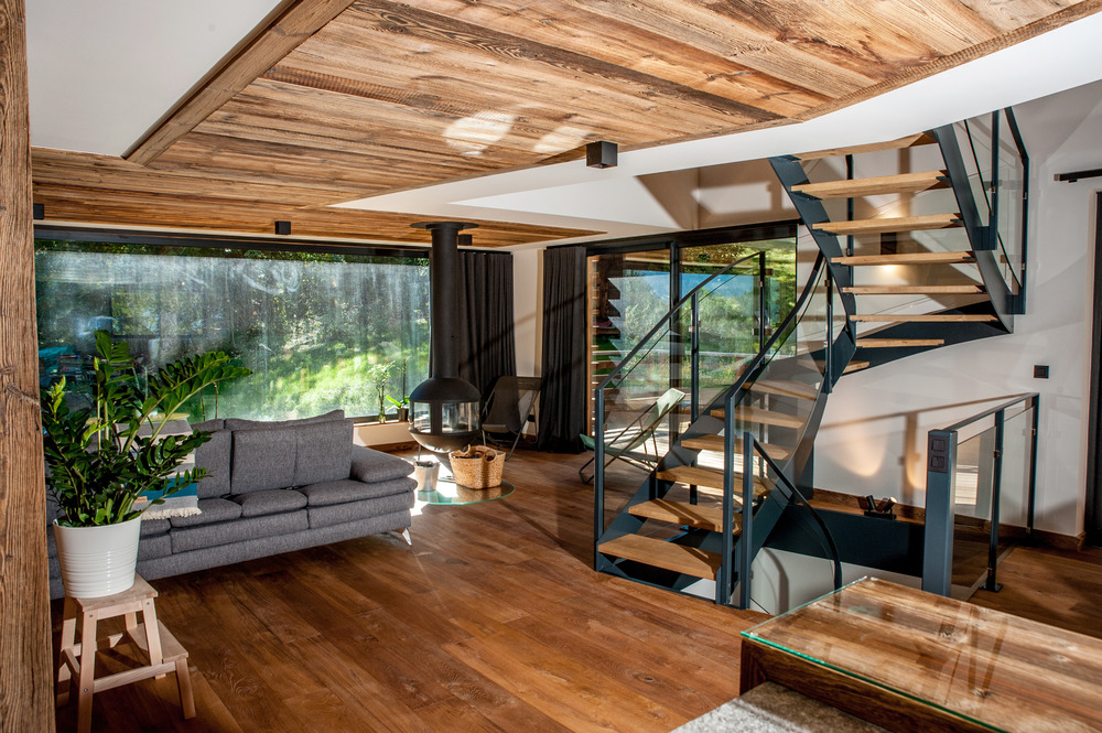 Moderný drevený interiér chaty s točitým schodiskom a výhľadom