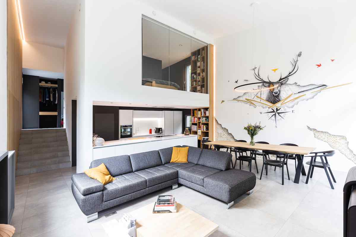 Moderná obývačka s vysokým stropom a preskleným boxom so spálňou