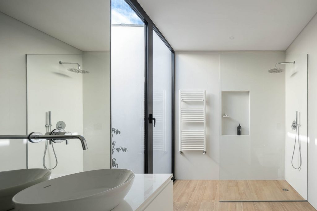 Biela kúpeľňa so svetlou podlahou a čiernym rámovaním dverí