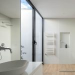Biela kúpeľňa so svetlou podlahou a čiernym rámovaním dverí