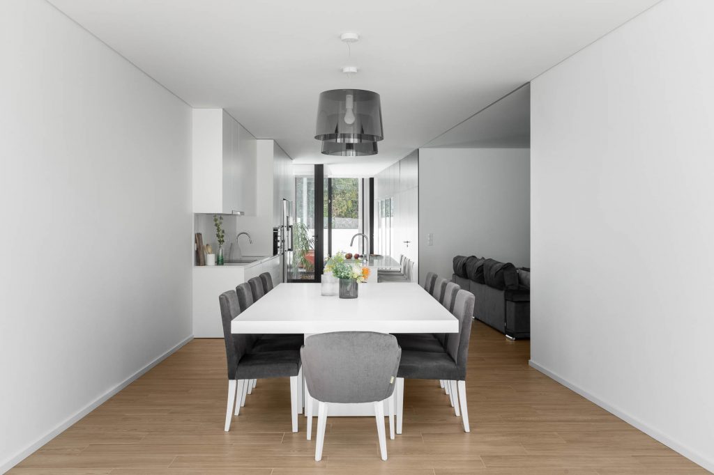 Moderná biela kuchyňa a jedáleň so svetlou podlahou vo vile