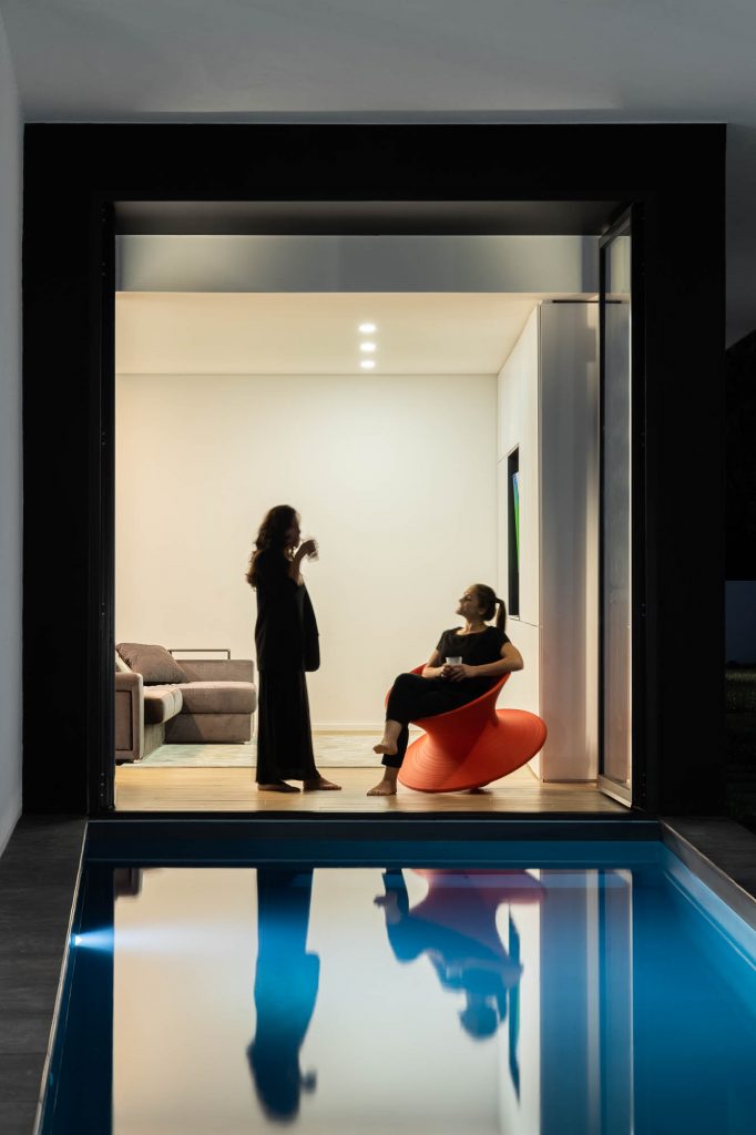 Pozdĺžny bazén pri geometrickej vile a ženy v interiéri
