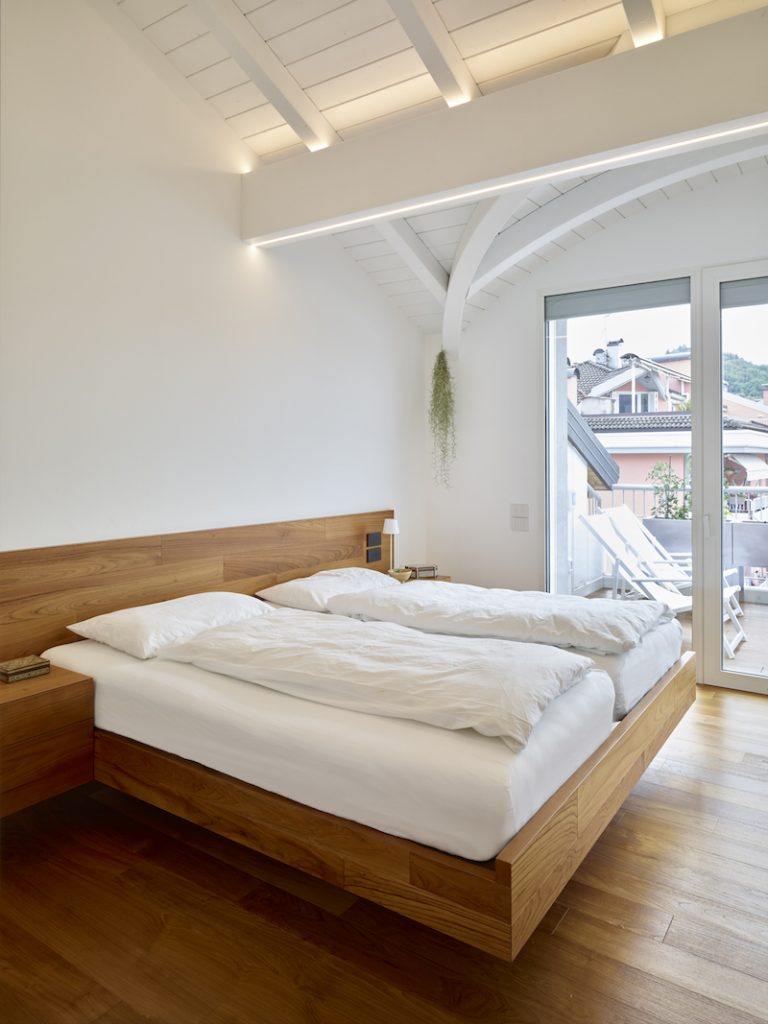 Biela spálňa s krovom a drevenou posteľou