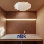 kúpeľňa z hnedého cementu s modrým vzorovaným umývadlom a okrúhlym svetlíkom