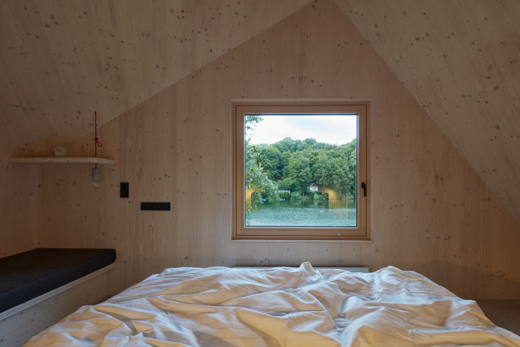 Podkrovná spálňa so šikmou strechou s oknom na priehradu