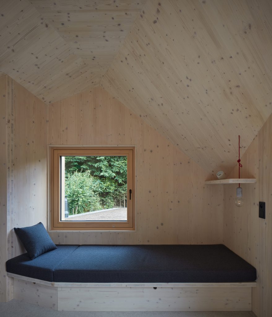Podkrovná izba s pohovkou so šikmou strechou s oknom na priehradu