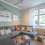 Tmavozelená sedačka v obývačke s designovým industriál svetlom