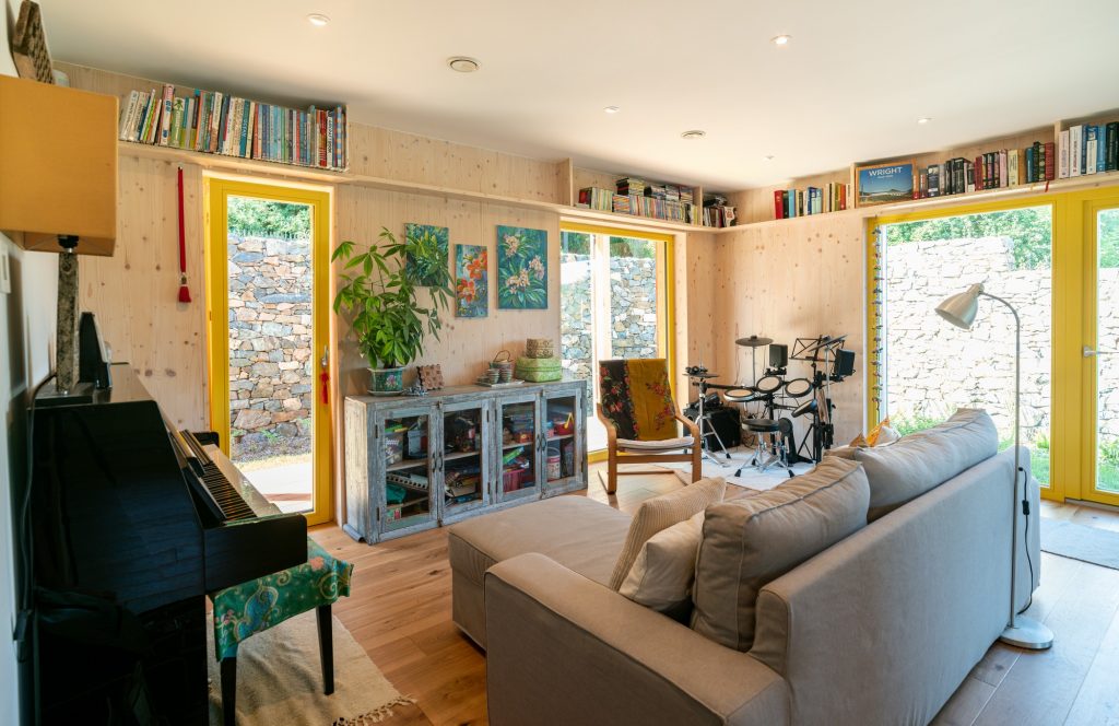 Obývačka s klavírom sivou pohovkou a troma francúzkymi oknami
