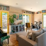 Obývačka s klavírom sivou pohovkou a troma francúzkymi oknami