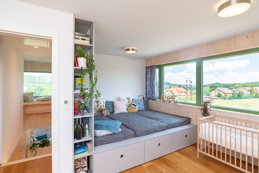 Jednoduchá spálňa s veľkým oknom postieľkou a posteľou s úložným priestorom