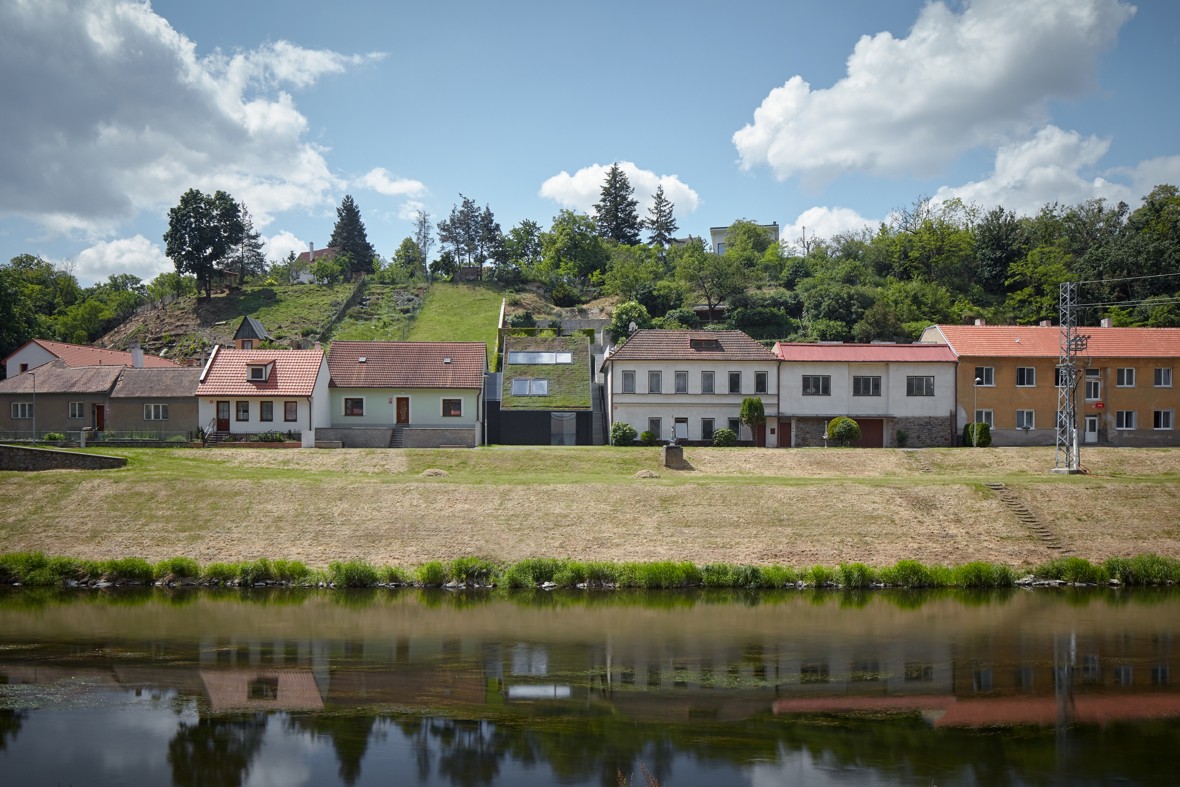 Na svahovitom teréne v prieluke medzi rodinnými domami vyrástol dom, ktorý je navrhnutý na pôdoryse úzkeho obdĺžnika s orientáciou na sever.