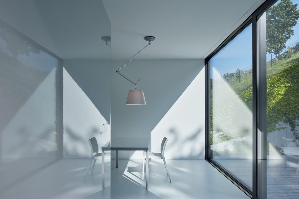 Moderný dom s minimalistickou bielou jedálňou s východom na terasu