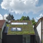 Rodinný dom so zelenou strechou medzi domami