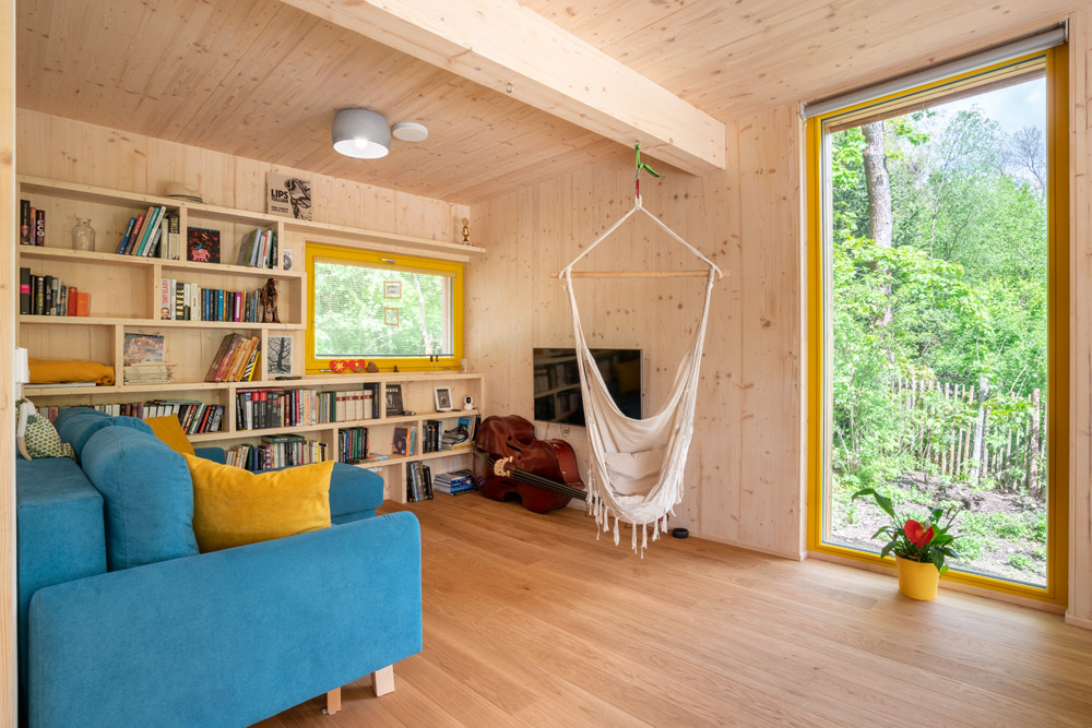 Obývačka v drevostavbe s knižnicou a tyrkysovým gaučom
