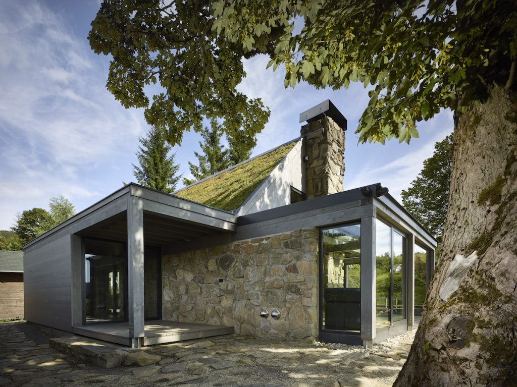Domček s mohutným kamenným komínom, zelenou strechou a zimnou záhradou
